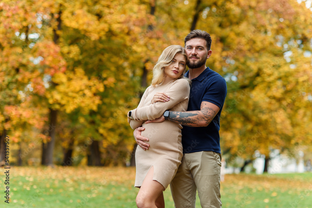 Young pregnant woman and her handsome husband are walking at the autumn park. Young pregnant woman and her handsome husband are walking at the autumn park.