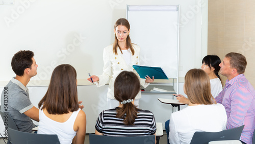 Woman reading out report to colleagues on meeting in office