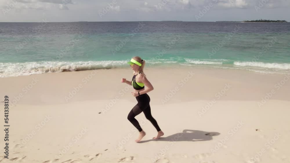 Aerial tracking shot of young woman jogging along coastline. Running activity is a very popular as healthy lifestyle. Aerial tracking shot of young woman jogging along coastline. Running activity is a very popular as healthy lifestyle.