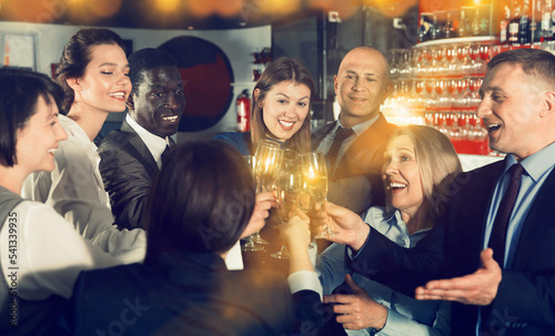 International group of cheerful positive smiling businesspeople toasting with champagne, having fun at office party in nightclub