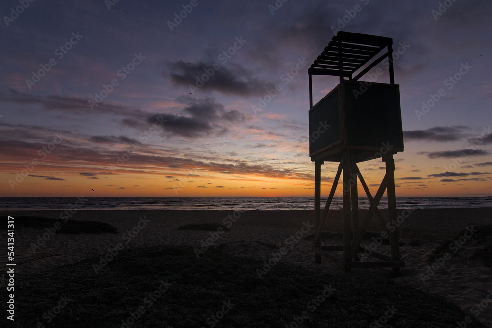 caseta del salvavidas en la playa bajo la puesta de sol de un cielo semi nublado