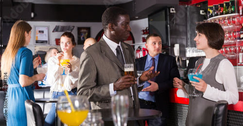 Respectable African man enjoying conversation with female colleague on corporate party in bar