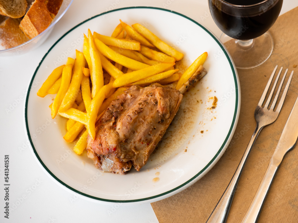 Appetizing braised pork knuckle served with vegetable garnish of crispy french fries.