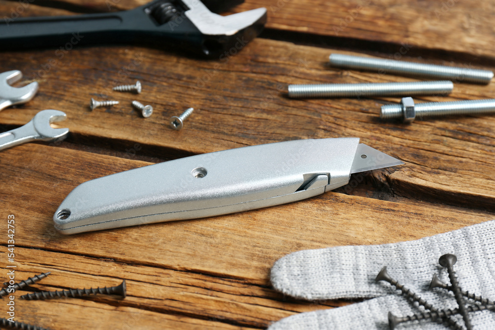 Utility knife and different tools on wooden table