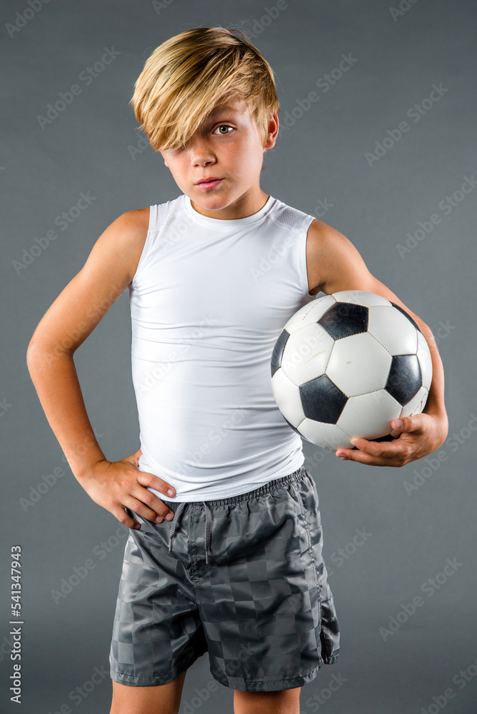 Boy standing relaxed hand on hip and holding a soccer ball Boy standing relaxed hand on hip and holding a soccer ball