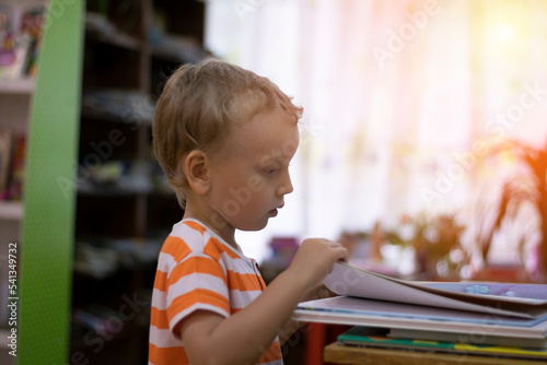 A preschooler examines a book in the reading room, a boy reads a children's book. Library