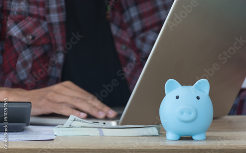 Saveing money concept,piggy bank on work table and worker man background,selective focus.