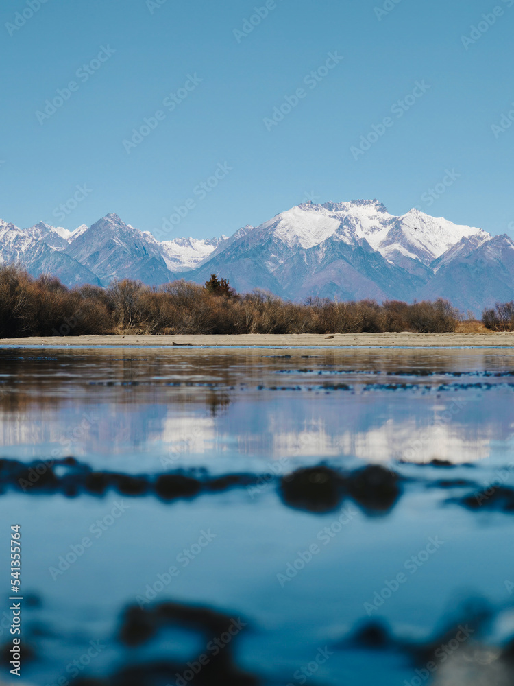Snow-capped mountains are reflected in the water of the lake