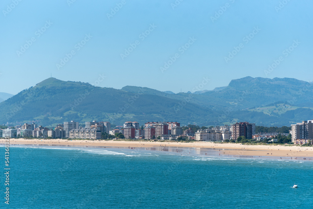 Vista panorámica de Laredo con altos edificios frente a la costa y la playa de arena blanca, con el mar turquesa y en calma, tomada desde Santoña en Cantabria.