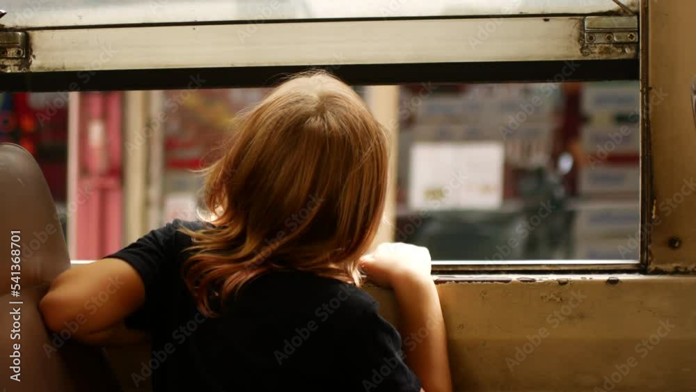 The child rides the bus and looks out the window