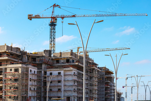 View of unfinished buildings, industrial cranes and lamps