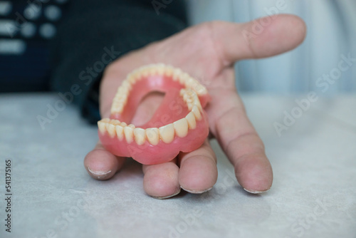 close-up in the hands of male dentures. Selective focus. False jaw, dental prosthetics. pensioner holding dentures in hand