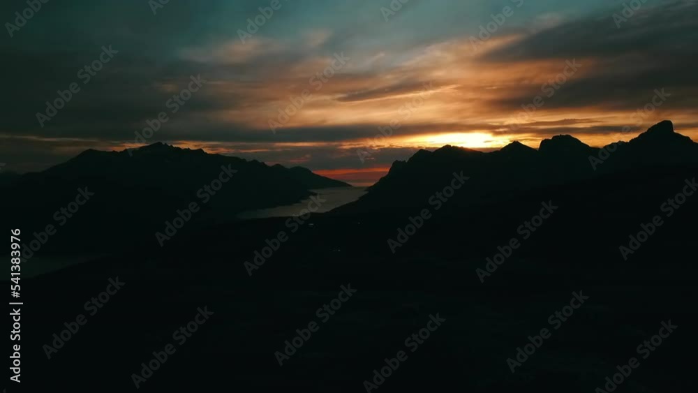 Aerial Panning Shot Of River Amidst Silhouette Of Rock Formations Under Dramatic Sky At Sunset - Tromso, Norway Aerial Panning Shot Of River Amidst Silhouette Of Rock Formations Under Dramatic Sky At Sunset - Tromso, Norway