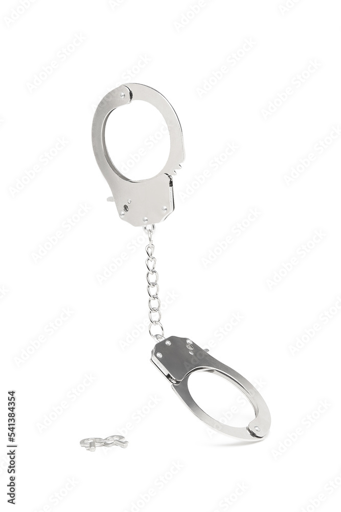 Close-up shot of metal handcuffs with an adjoining chain and metal unlocking keys. The metal handcuffs are isolated on a white background. Front view. Close-up shot of metal handcuffs with an adjoining chain and metal unlocking keys. The metal handcuffs are isolated on a white background. Front view.