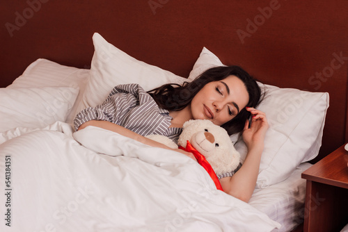 A brunette woman hugs an ivy bear in a dream. Healthy sleep photo