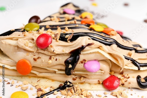 Φωτογραφία Close-up view of rFench crepes with colorful candies and chocolate syrup topping