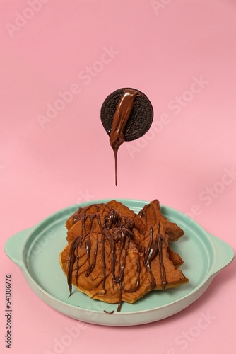 Vertical view of fish-shaped Taiyaki cones on a blue plate with chocolate syrup and a cookie on top