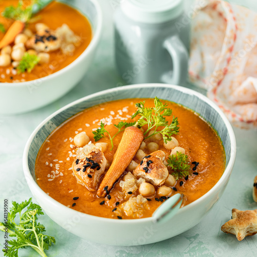 Pumpkin cream soup. Pumpkin and carrot puree soup with chickpeas and quinoa on a green background. Vegetarian cuisine. Vegan recipes.