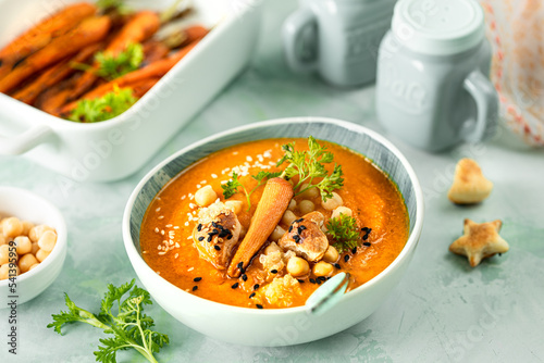 Pumpkin cream soup. Pumpkin and carrot puree soup with chickpeas and quinoa on a green background. Vegetarian cuisine. Vegan recipes.