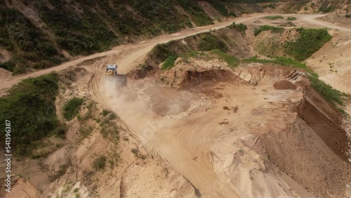 Dump truck transported sand from the open pit. Truck with tipper semi trailer working in quarry. Arial view of the opencast mine. Sand and gravel is excavated from ground. Mining industry. 
 photo