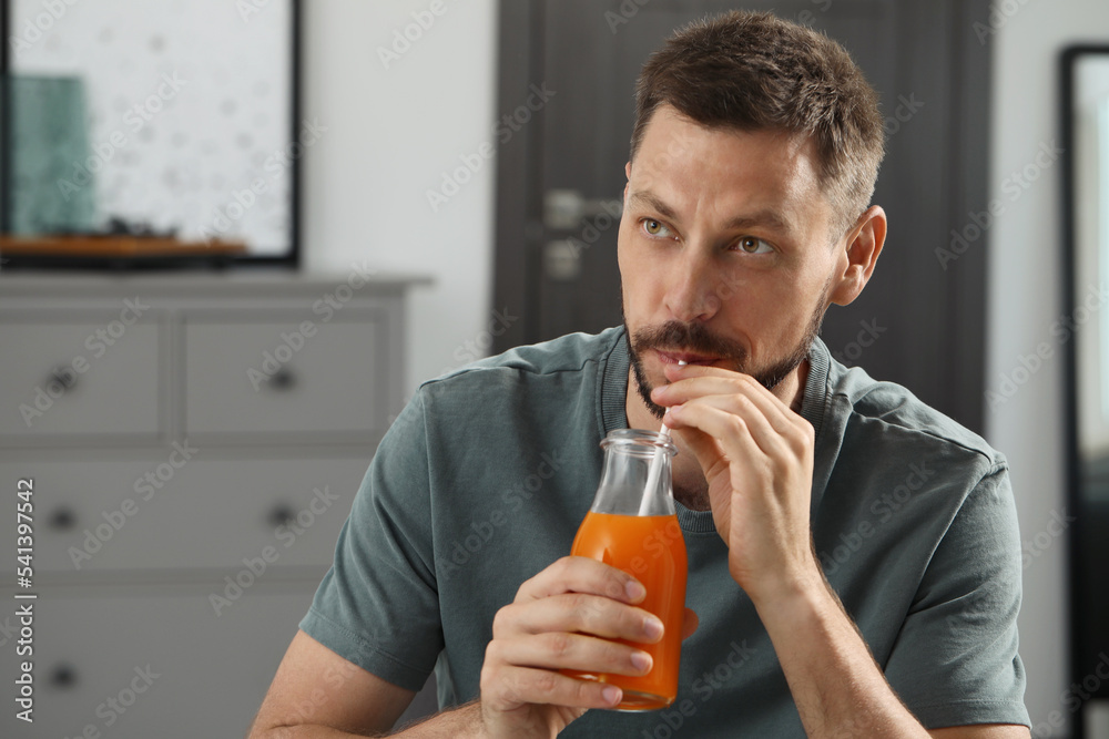 Man drinking delicious juice at home, space for text Man drinking delicious juice at home, space for text