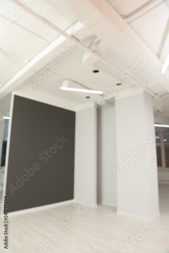 Blurred view of empty office room with color walls and modern lights on ceiling. Interior design