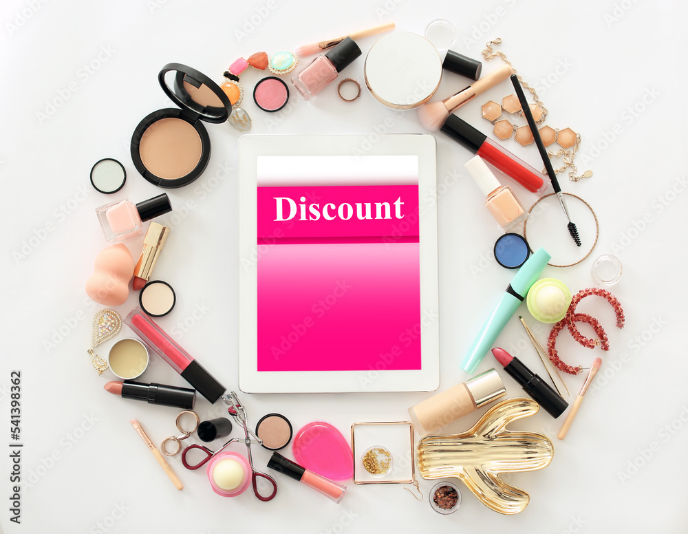 Tablet with word Discount and makeup products on light background, flat lay Tablet with word Discount and makeup products on light background, flat lay