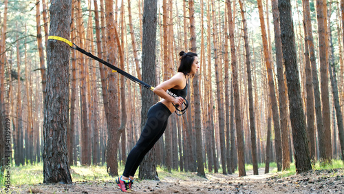 Beautiful  athletic  sexy young woman  coach  instructor  performs exercises  doing exercises. In pine forest  in summer  in sun rays. High quality photo