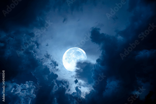 Night sky with full moon. Dramatic clouds in mystic moonlight. Large bright moon as concept of mystery, midnight, gothic time and spooky theme.