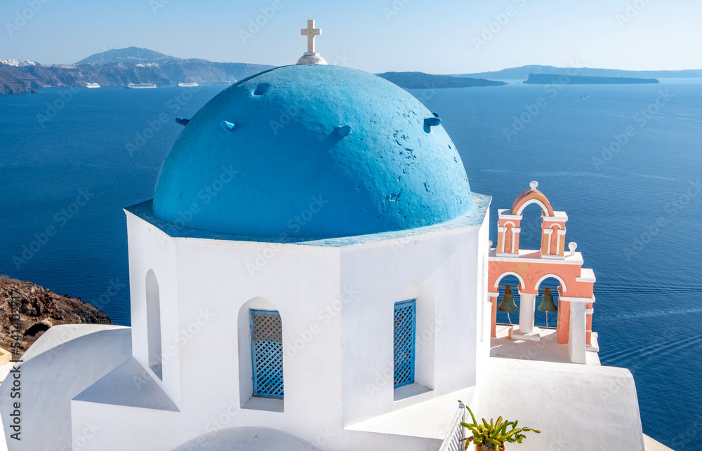Iconic blue domed church and pink bell tower in Oia town on Santorini island