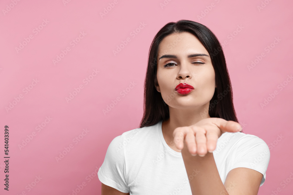 Beautiful young woman blowing kiss on pink background. Space for text Beautiful young woman blowing kiss on pink background. Space for text