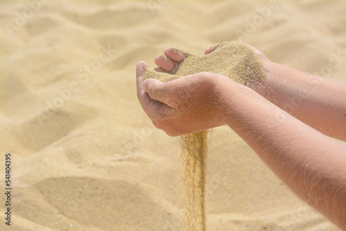 Fotografi Child pouring sand from hands on beach, closeup with space for text