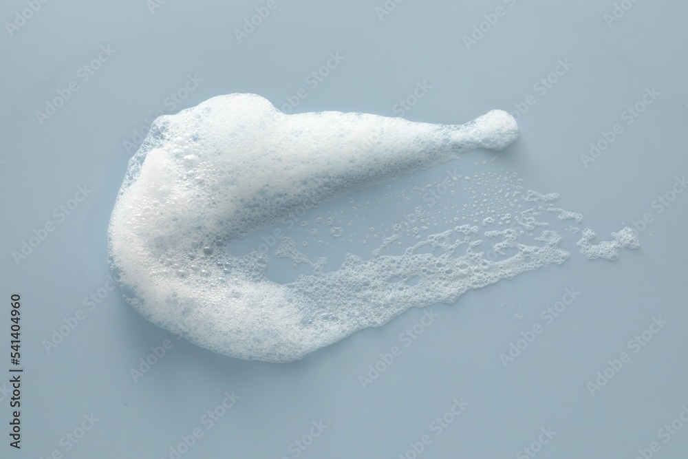 Fototapeta premium Smudge of white washing foam on color background, top view