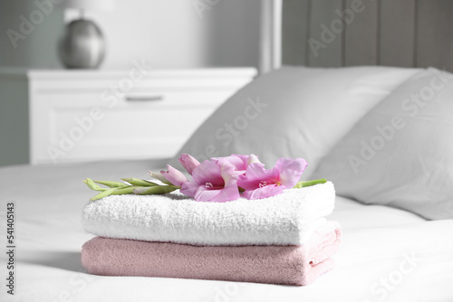 Terry towels with beautiful flower on bed indoors, space for text