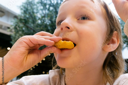 Child looks up and eats nuggets. close-up