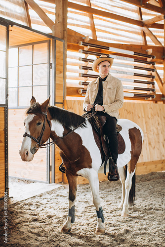 Handsome cowboy man riding a horse on a ranch.