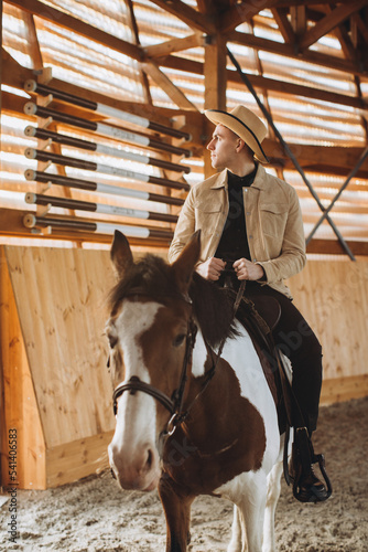 Handsome cowboy man riding a horse on a ranch. © dsheremeta