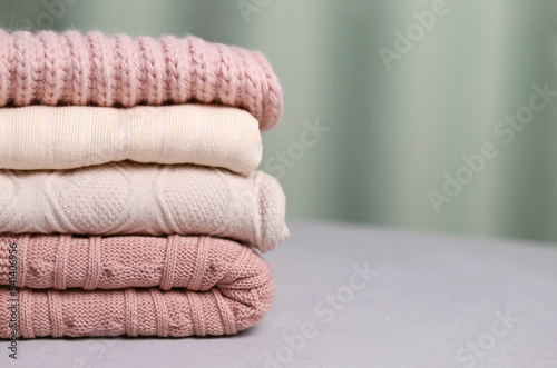 A stack of warm knitted things on a gray background. Selective focus. Copy space