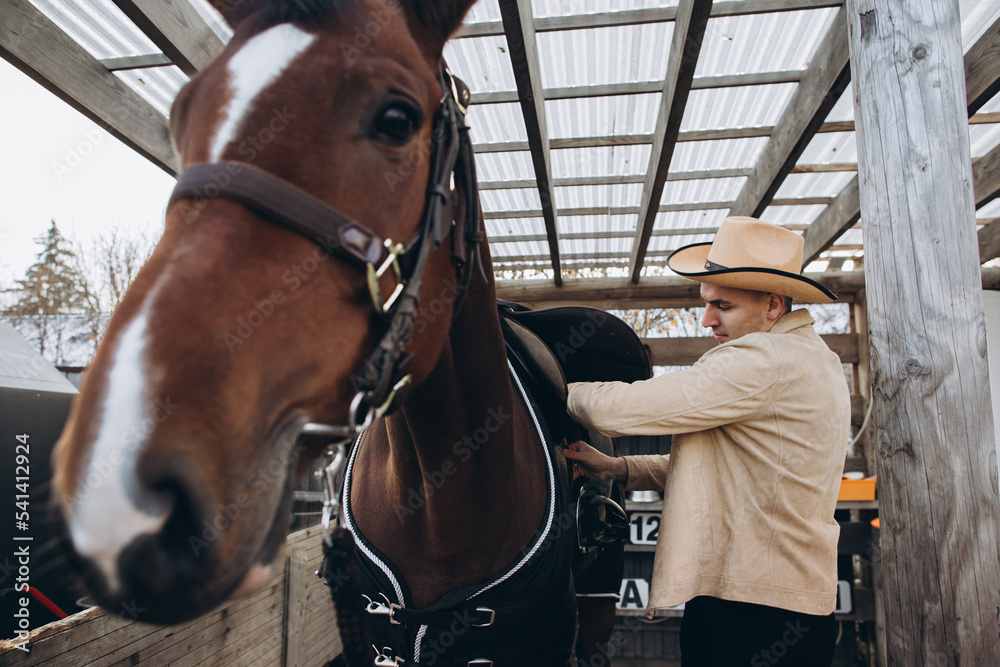 Fototapeta premium Handsome young cowboy on a ranch with a horse.