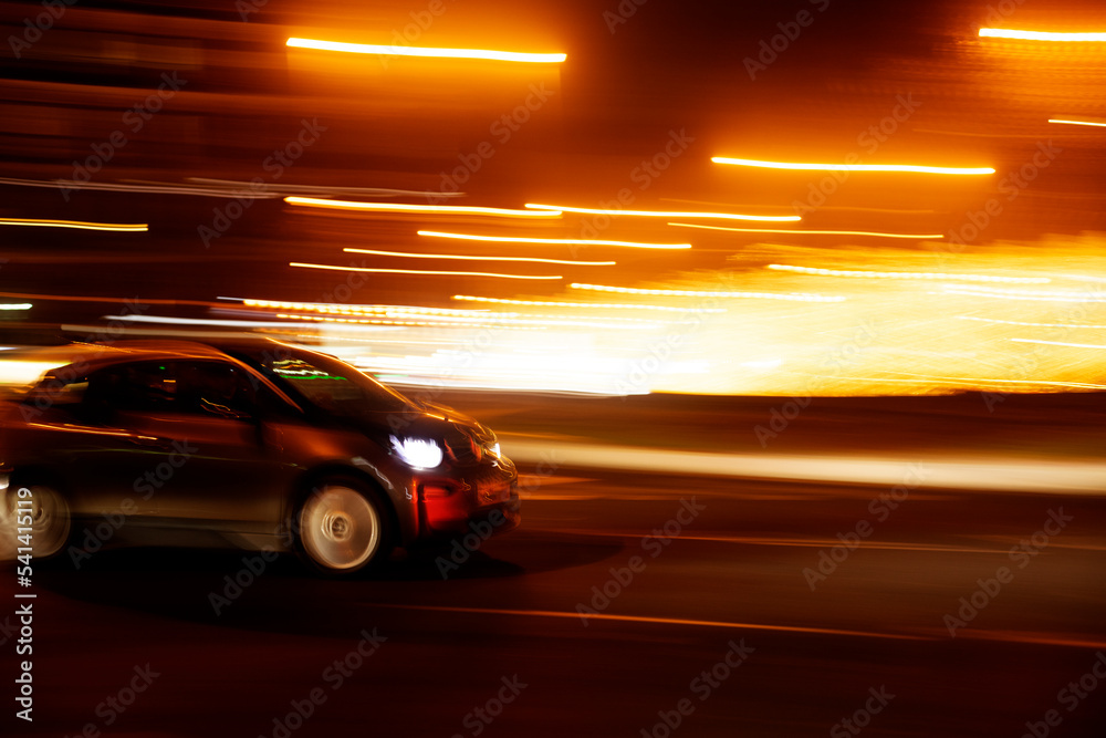 compact car at speed on the street with nighttime light trails