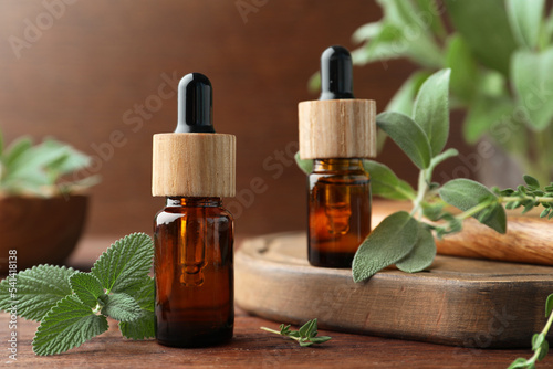Fototapeta Naklejka Na Ścianę i Meble -  Bottles of essential oils and fresh herbs on wooden table