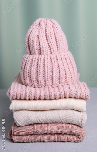 A knitted hat on a stack of sweaters. Vertical photo. Warming clothes.