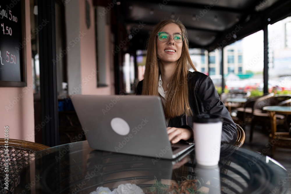 young female freelancer working on a laptop remotely in a cafe young female freelancer working on a laptop remotely in a cafe