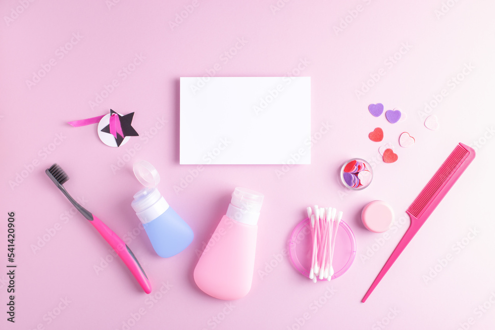 Teenage girl self care cosmetics and white paper card with blank space isolated on pastel pink background. Beauty, fashion, concept.