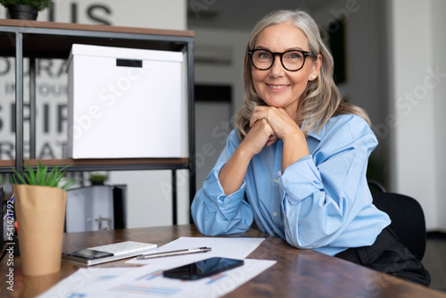 Photography Successfully Middle aged older business woman head sits at a table and looks at