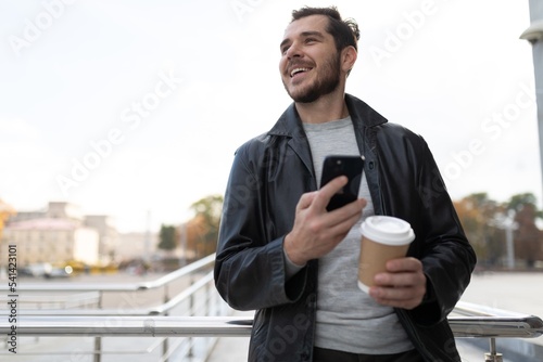 a man with a mobile phone in the city drinking coffee