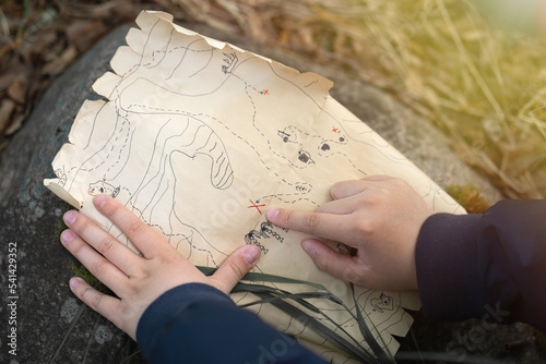 Pirate treasure map for kids.A family treasure hunting game. Outdoor games for the whole family. A treasure hunt quest. The child\'s hand points to the place with the treasure.