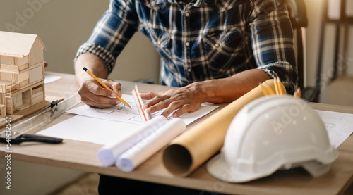 business man hand working and laptop with on on architectural project at construction site at desk in office