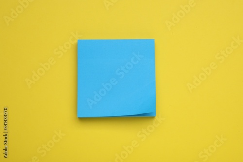 Paper note on yellow background, top view