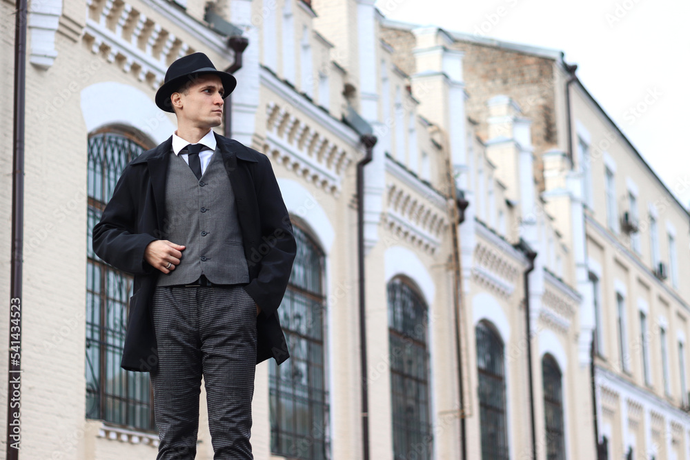 Men's photo shoot in a classic plaid suit and a hat against the backdrop of an old building. Men's photo shoot in a classic plaid suit and a hat against the backdrop of an old building.